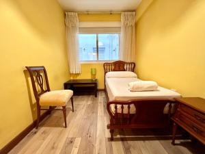 a room with two beds and a chair and a window at VibesCoruña - Bergondo 10 in A Coruña