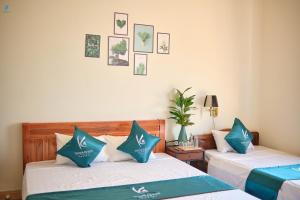 two beds in a room with pictures on the wall at Kim's Homestay & Villa in Ha Long