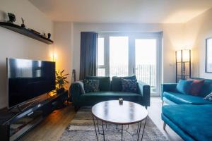 Beautiful & Contemporary Queensbury Retreat في Wealdstone: غرفة معيشة مع أرائك زرقاء وطاولة قهوة