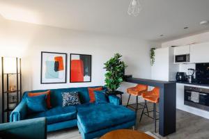 a living room with a blue couch and a kitchen at Beautiful & Contemporary Queensbury Retreat in Wealdstone