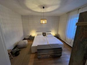 una camera da letto con un grande letto bianco e un lampadario a braccio di sennefeeling a Hövelhof
