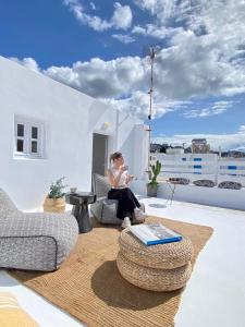 een vrouw op een stoel op een balkon bij Mykonos be Chic Luxury Mansion in Mykonos-stad