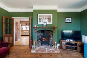 a living room with a fireplace and a tv at FIRS Sleeps 15 Stunning country house with hot tub in Sudbourne