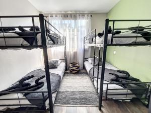 a bedroom with three bunk beds and a window at Appart XXL -10 pers - 2 Pkg - 10 mn Paris in Épinay-sur-Seine