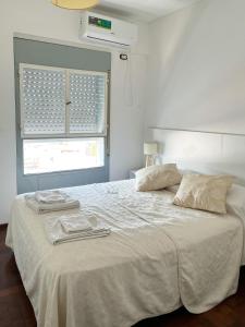 a bedroom with a white bed with two towels on it at EL ENCANTO DEL CENTRO CORAZÓN DE SANTA FE ARGENTINA in Santa Fe