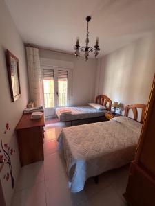 a bedroom with two beds and a table and a window at Piso para familias numerosas in Garray