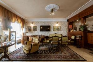 a living room with a couch and chairs and a tv at Allegro Hotel in Ljubljana