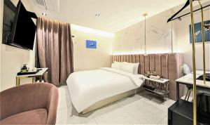 una camera con un grande letto bianco e una sedia di Denbasta Hotel a Busan