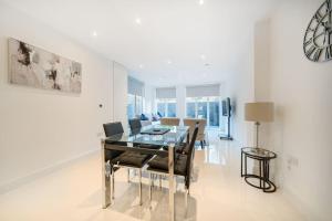 倫敦的住宿－Amazing 3 Bedroom Flat in the Heart of Wimbledon，一间设有玻璃桌和椅子的用餐室