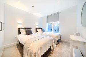 倫敦的住宿－Amazing 3 Bedroom Flat in the Heart of Wimbledon，白色客房的两张床,设有窗户