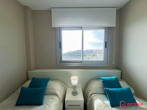 een slaapkamer met een bed met blauwe kussens en een raam bij Calma y Relax en el Mediterráneo in Cabanes
