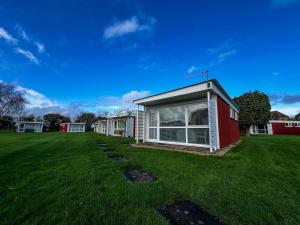 a house in a yard with a green lawn at Lovely 4 Berth Chalet In The Coastal Village Of Heacham, Ref 92018cs in Heacham