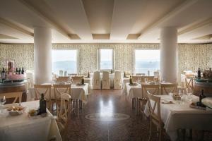 ein Restaurant mit weißen Tischen und Stühlen und Fenstern in der Unterkunft CRICHELON in Altavilla Vicentina