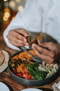 a person holding a piece of food over a pan of food at Bharat Vandana Stay near Yashobhoomi in New Delhi