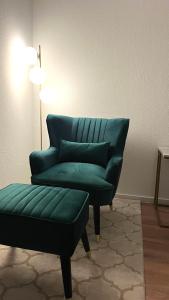 una silla verde y un reposapiés en una habitación en City Appartement direkt am Schloss!, en Karlsruhe