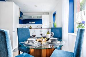 uma sala de jantar com cadeiras azuis e uma mesa com copos de vinho em Sapphire Retreat - Central Location - Free Parking, FastWiFi and Smart TV by Yoko Property em Derby