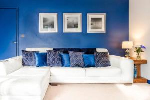 un sofá blanco con almohadas azules en la sala de estar. en Sapphire Retreat - Central Location - Free Parking, FastWiFi and Smart TV by Yoko Property en Derby