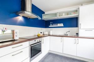 cocina con armarios blancos y paredes azules en Sapphire Retreat - Central Location - Free Parking, FastWiFi and Smart TV by Yoko Property en Derby