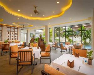a restaurant with white tables and chairs and windows at Angkor Style Resort & Spa in Phumi Ta Phul