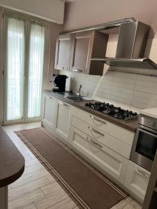 La cuisine est équipée de placards blancs et d'un four avec plaques de cuisson. dans l'établissement Appartamento Via Milano Prato, à Prato