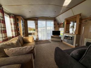sala de estar con sofá y TV en Great Caravan For Hire With Pond Views At Manor Park Holiday Park Ref 23228k, en Hunstanton