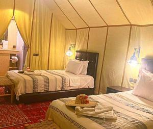 a bedroom with two beds and a hat on top at Merzouga luxury magic nights in Merzouga