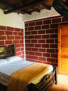 a brick walled bedroom with a bed in a room at Hostal Los Wichos in Minca