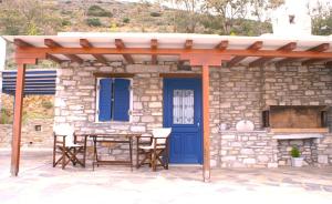 una casa in pietra con una porta blu e un tavolo con sedie di J&D Apartment a Kóstos
