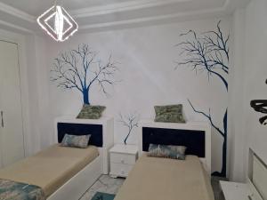 um quarto com duas camas e árvores na parede em Belhassen II em Tunes