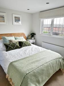 een slaapkamer met een bed met een groene deken en 2 ramen bij Gorgeous 1 bedroom & private ensuite in Central Windsor home with FREE PARKING in Windsor