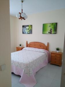 a bedroom with a bed with a pink bedspread at APARTAMENTO PUERTO GOLF in Almerimar