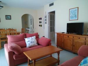 uma sala de estar com um sofá vermelho e uma televisão em APARTAMENTO PUERTO GOLF em Almerimar