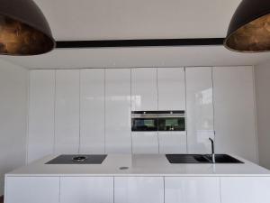 een witte keuken met een wastafel en een magnetron bij Volledige gezinswoning te huur in Mechelen