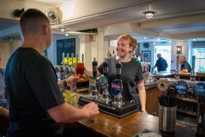 a woman standing at a bar with a bartender at The Ship Hotel in New Romney