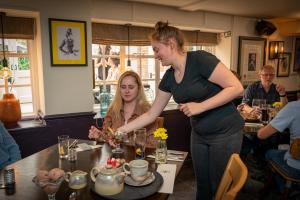 a woman standing at a table in a restaurant at The Ship Hotel in New Romney