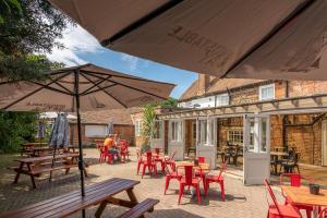 an outdoor patio with tables and chairs and an umbrella at The Ship Hotel in New Romney