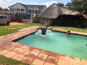 two people in a swimming pool in a yard at Garden View Guesthouse Klinker in Johannesburg