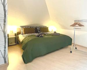 Un dormitorio con una cama verde con dos animales de peluche. en Femo SCHICK-modern, Natur, Rothaarsteig, 2Etg, 2Bäder, en Burbach