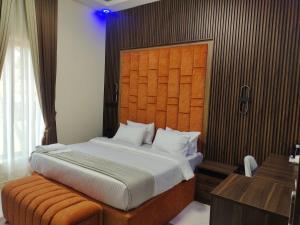1 dormitorio con 1 cama grande y cabecero de madera en Passready Hotel and Suites Nnewi, en Nnewi