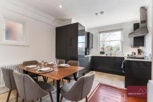 a kitchen and dining room with a table and chairs at Kew Village- Modern Pets Welcome 3Bed in Richmond upon Thames