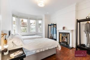 a white bedroom with a bed and a fireplace at Kew Village- Modern Pets Welcome 3Bed in Richmond upon Thames