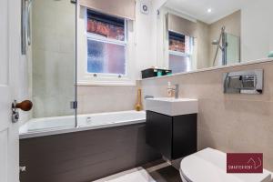 a bathroom with a sink and a tub and a toilet at Kew Village- Modern Pets Welcome 3Bed in Richmond upon Thames
