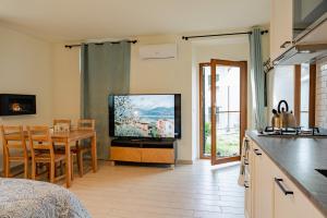 eine Küche und ein Wohnzimmer mit einem TV und einem Tisch in der Unterkunft Casa Galya with private patio by GardaDoma in Brenzone sul Garda