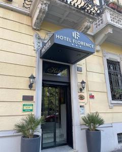 ミラノにあるHotel Florence Milanoの鉢植えの植物が2本入った建物の前のホテル入口
