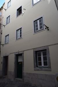 a white building with a green door and windows at Acolhedor Apartamento Em Alfama in Lisbon