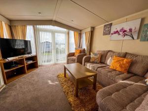 a living room with a couch and a tv at Lovely Caravan At Manor Park, Nearby Hunstanton Beach In Norfolk Ref 23067s in Hunstanton
