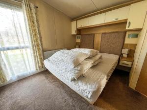 a small bed in a room with a window at Lovely Caravan At Manor Park, Nearby Hunstanton Beach In Norfolk Ref 23067s in Hunstanton
