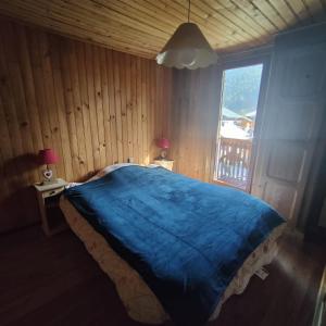 Un dormitorio con una gran cama azul y una ventana en Chalet l Abondance, en La Chapelle-dʼAbondance