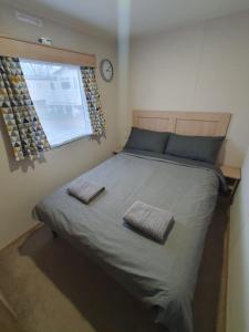 a bedroom with a large bed with two towels on it at Escape City Caravan in Lytchett Minster