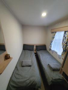 a small room with two beds and a window at Escape City Caravan in Lytchett Minster
